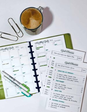 a desk with a cup of coffee and a monthly goal planner